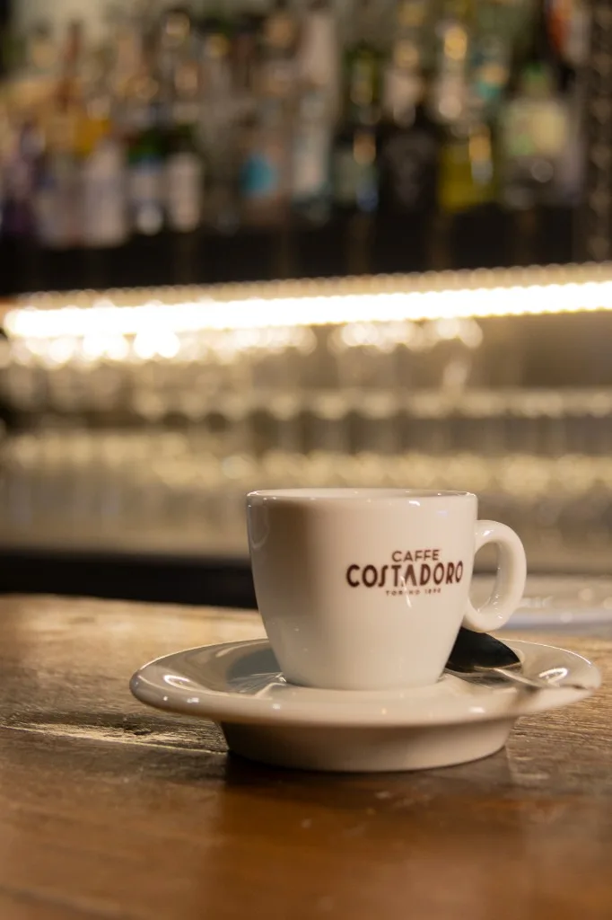 Tazzina da espresso sul bancone, con i bicchieri sullo sfondo